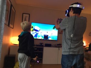To av guttene spiller VR sammen, en med headsetttet, den andre uten.